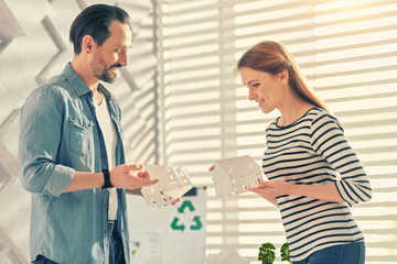 Our result. Pleased girl standing in semi position and holding artificial building