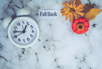 Fall Daylight Saving Time concept with white clock and flowers, flat lay