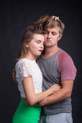 Beautiful young couple hugging and kissing isolated on black background.