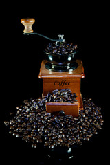 Coffee beans and vintage wooden coffee grinder on black background.