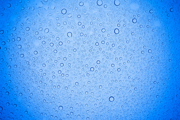 Rain droplets on blue glass background, Water drops on blue glass.