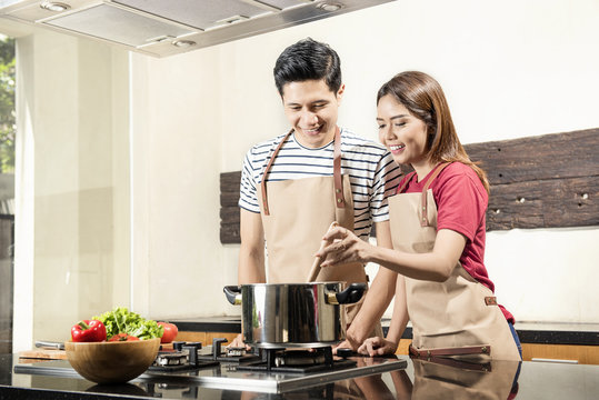 Cheerful asian couple cooking together