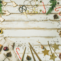 Getting ready for Christmas or New Year party. Flat-lay of holiday decoration toys, candles, rope, garlands, tree branches, sweater, candy cane over white background, top view, copy space, square crop