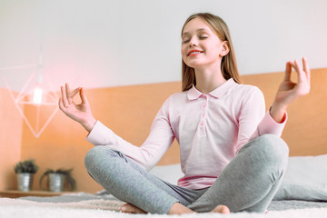 Keep calm. Charming girl expressing positivity while leaning arms on knees and closing eyes