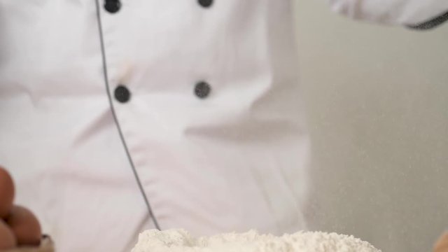 Young chef clapping his hands filled with flour, slow motion