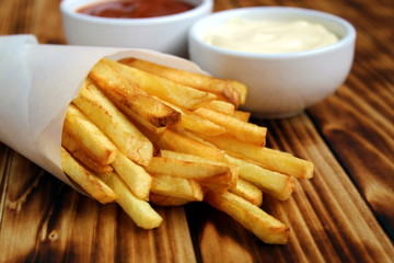 French fries wrapped in paper and two kinds of sauce
