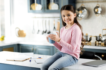 Break from study. Cheerful jovial girl holding cup and looking at camera