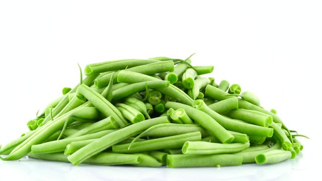 Heap of fresh cut green beans. Rotating on the turntable. Isolated on the white color background. Close-up. Macro.