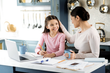 Mother support. Vigorous ambitious girl studying and woman tapping her on head