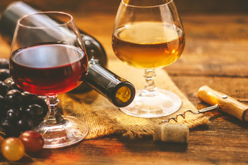 A bottle of wine on a background of glasses and grapes on a wooden table