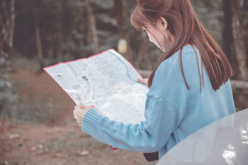 Woman traveler looking map in forest.