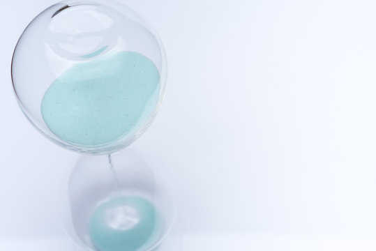 Hourglass on white background. Sand falls inside the flask.