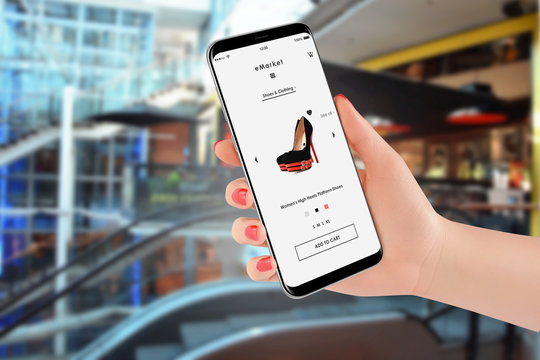 Girl buying high heels online on her smartphone. Shopping mall in background