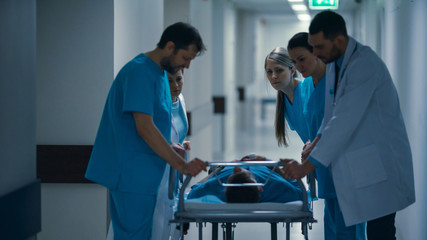 Obraz premium Emergency Department: Doctors, Nurses and Paramedics Push Gurney / Stretcher with Seriously Injured Patient towards the Operating Room. Bright Modern Hospital with Professional Staff Saving Lives.