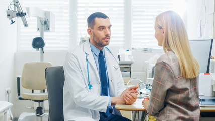 In Medical Office Concerned Doctor Talks with a Beautiful Blonde Woman. Health Care Professional...