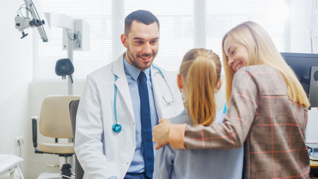 Friendly Doctor Does Routine Examination of a Sweet Little Girl who Came with Her Mother. Pediatrician Talks to Both of them. Doctor's Office is Bright and Modern.