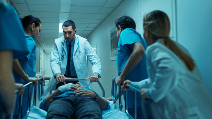 Emergency Department Doctors, Nurses and Surgeons Move Seriously Injured Patient Lying on a Gurney...