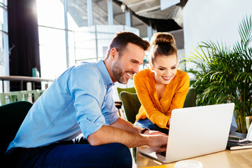 Two smiling creative workers discussing project during meeting in cafe