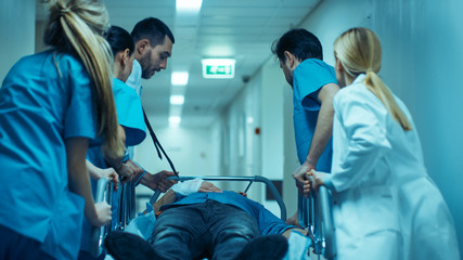Emergency Department: Doctors, Nurses and Surgeons Move Seriously Injured Patient Lying on a...