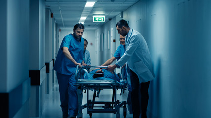 Emergency Department: Doctors, Nurses and Paramedics Run and Push Gurney / Stretcher with Seriously Injured Patient towards the Operating Room. Modern Hospital with Professional Staff.