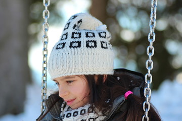 Bambina in altalena sulla neve