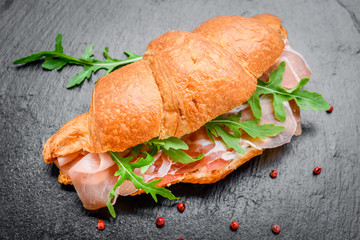 Fresh croissant with ham and salad leaf