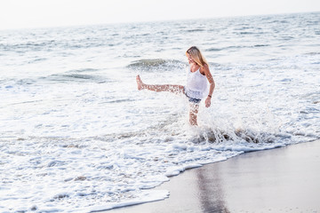 Attractive happy mature tourist woman playful jumping splashing on asian sand tropical beach.