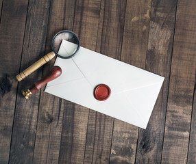 Blank envelope, stamp and magnifier on wooden background. Flat lay.