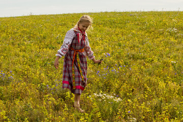 a girl in a Russian folk costume walks the field in a warm autumn afternoon