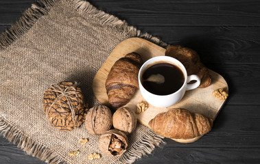 coffee with croissants and broken walnuts on the table