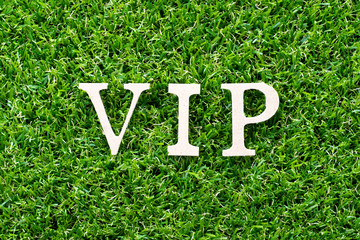 Wood letter in word VIP (abbreviatino of very important person) on artificial green grass background