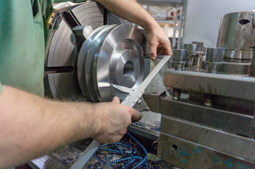 A worker, a man makes measurements of a part with a measuring instrument. Turning work in...