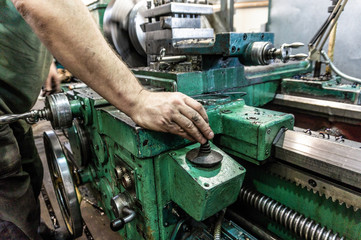 The worker, the man, makes mechanical actions of the machine control. Turning work in production.
