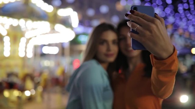 Girls take a selfie, women make mobile photos using smart phone at nigth city