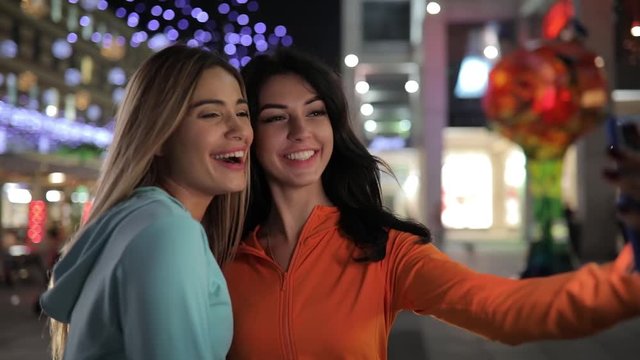 Girls take a selfie, women make mobile photos using smart phone