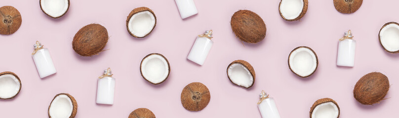 Pattern with ripe coconuts and coconut oil in a glass bottle on pink background minimal flat lay...