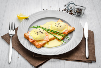Fried egg on bread for breakfast on plate and rustic table, with salmon