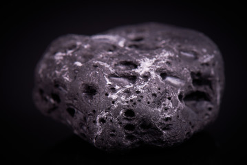 Black porous basalt stone on a black background
