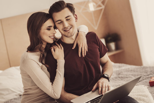 Relieved partners. Young love partners feeling extremely relieved while looking at shared photos on silver laptop together