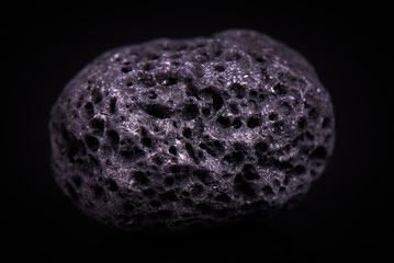Black porous basalt stone on a black background