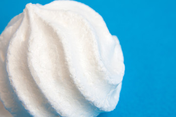 Part of a white zephyr or marshmallow on blue background. Macro