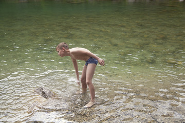 Boy standing in the river and splashing around