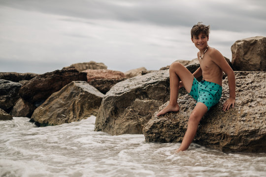 Smiling boy sitting on the beach rock