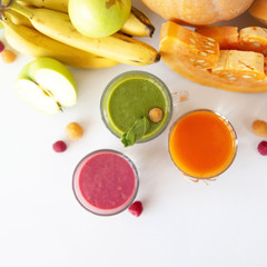 Autumnal vegetable and fruit smoothies on a white background next to pumpkin, spinach, banana, raspberries and apples. Diet, Detox and Vegetarian Food. Top view, flat lay