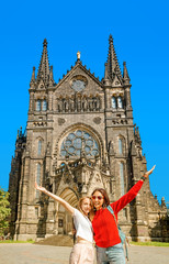 Two girls tourists friends hugging against the background of St. Peter's Church in Leipzig
