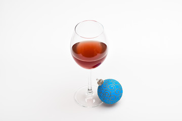 New year party concept. Wineglass with red liquid or wine and christmas ball ornament isolated on white background. Winter celebration with alcohol drink. Glass with wine and christmas decoration