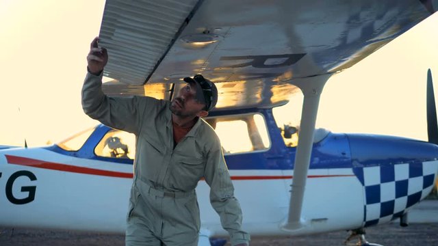 Male pilot checks airplane wings, close up.