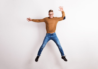 Portrait of a happy young man in a studio, jumping.