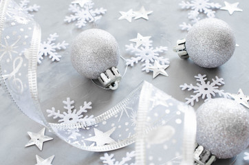 Silver Christmas background. Curly ribbon with decorative balls and snowflakes.