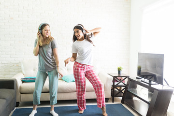 Female Friends Dancing While Listening To Music On Headphones